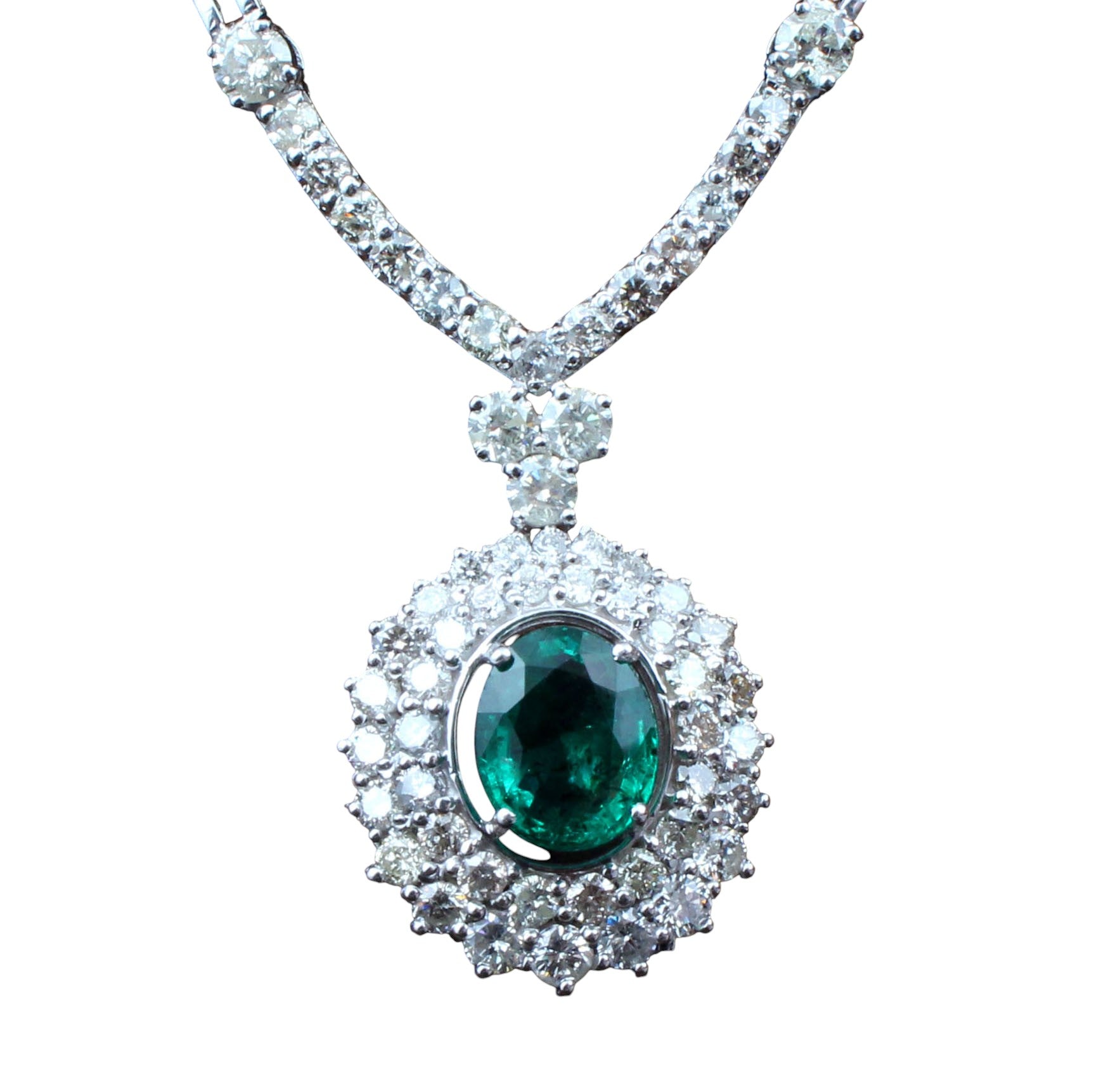 Diamond necklace with a central emerald stone on a white background